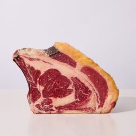 A thick-cut, bone-in 45-day dry-aged Rubia Gallega prime rib, showcasing deep red meat and rich marbling.