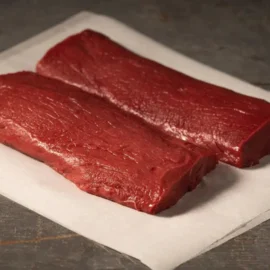 A close-up of a premium, boneless wholesale venison backstrap, showcasing its deep red color and lean texture.