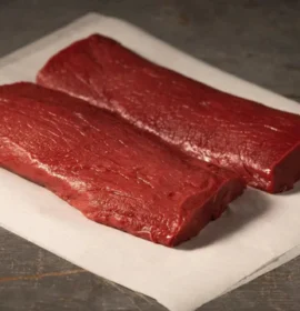 A close-up of a premium, boneless wholesale venison backstrap, showcasing its deep red color and lean texture.