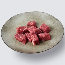 Cubes of fresh grassfed beef dice in a bowl, ready for cooking.