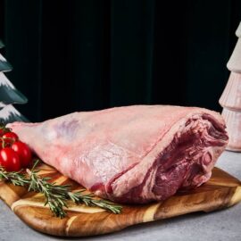 A succulent, perfectly roasted bone-in Lamb Leg Roast, ready to be carved on a wooden board.