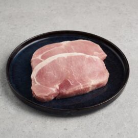 A close-up of thick, fresh pork loin chops with beautiful marbling, ready for cooking.