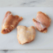 A bulk case of individually quick-frozen chicken thighs, ready for sale.