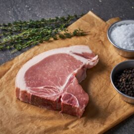 A thick, marbled Dingley Dell Pork T-Bone Steak, raw and ready for cooking.