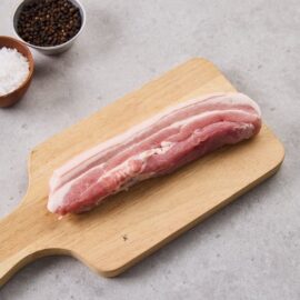 A premium slab of free-range pork belly with skin-on, showcasing layers of meat and fat, ready for cooking.