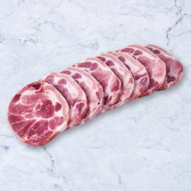 Close-up of several raw, well-marbled frozen pork collar steaks arranged neatly on a dark surface.