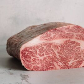 A perfectly marbled Robbins Island Tasmanian Wagyu Ribeye Steak MB9+ on a dark surface.