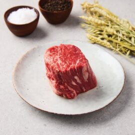 A perfectly cooked, thick-cut USDA Prime Fillet Steak resting on a cutting board, showcasing its juicy, pink interior and rich marbling.