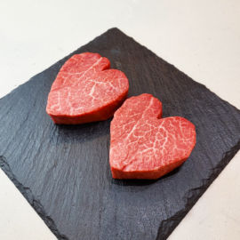 A pair of perfectly marbled Valentines Wagyu Steaks presented on a dark surface, ready for cooking.